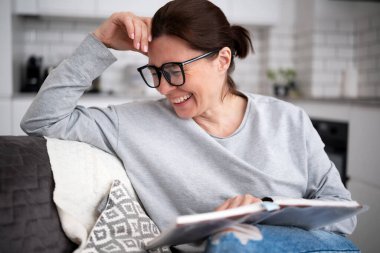 Mutlu genç kadın kitap okuyor ve gülüyor.