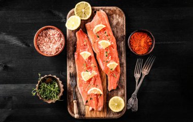 Limonlu ve baharatlı çiğ alabalık fileto balığı kesim tahtasında pişmeye hazır.