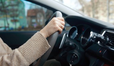 Elleri direksiyonda, araba süren bir kadın.