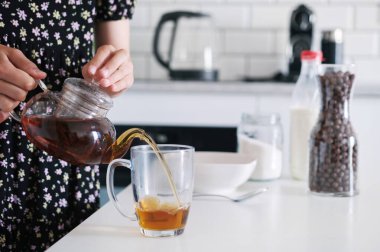 Küçük kız mutfakta kahvaltıda siyah çay yapıyor.