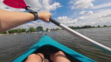 Adam gölde kano kullanıyor, kürekle kürek çekiyor, açık hava su sporlarının tadını çıkarıyor.