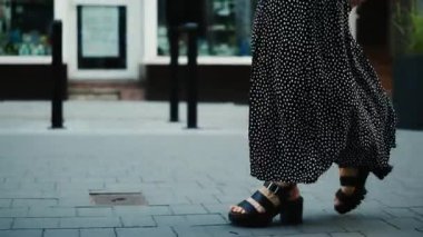 Kaliteli hafif elbiseli ve yüksek topuklu ayakkabılı bir kız Avrupa 'nın tarihi bölgelerinde yürüyor.