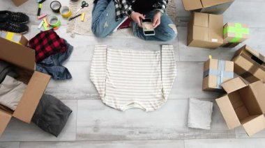 Kız, onları internette satabilmek için sahiplenilmiş kıyafetlerin fotoğraflarını çekiyor ve kullanılmış eşyaları satmaya odaklanıyor.