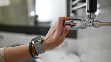 Kız banyodaki radyatör sıcaklığını ayarlıyor.