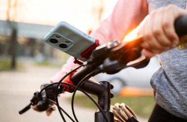 Gün batımında, Akıllı Telefonlu Bir Bisiklet Kolundaki Kadın Eller