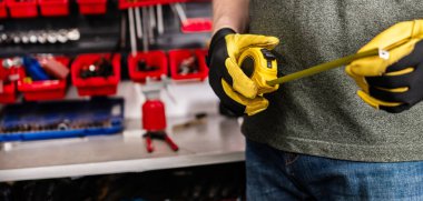 Koruyucu Eldivenli Adam çalışma masasında bir mezura tutuyor.