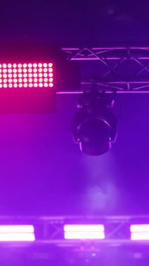 Tavandaki spot ışıkları konser sahnesini ve çalışmalarını aydınlatıyor. Şov boyunca, dikey video