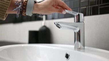 Kız lavaboyu açar lavabo musluğu ve musluktan su akar.