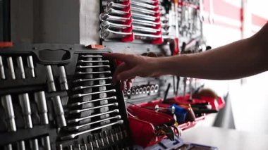 Adam garajda çeşitli aletlerle rafta bir düğme seçiyor.