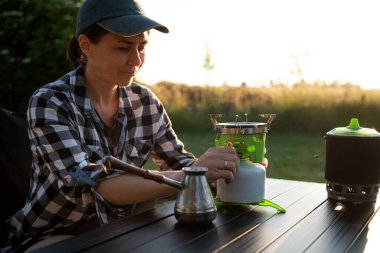 Cezaevinde kahve yapan kadın portatif kamp ocağında su kaynatıyor.
