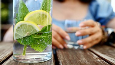 Naneli ve limonlu bir kavanoz taze su bir kafe masasına oturur.