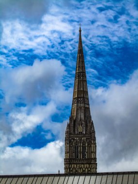 Steeple of Salisbury Cathedral, United Kingdom with blue cloudy sky clipart