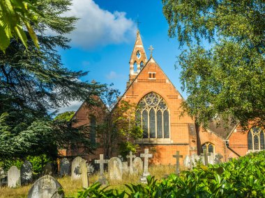 St Johns Church Crowthorne Berkshire UK. Blue sky showing windows and steeple, trees and grave yard clipart