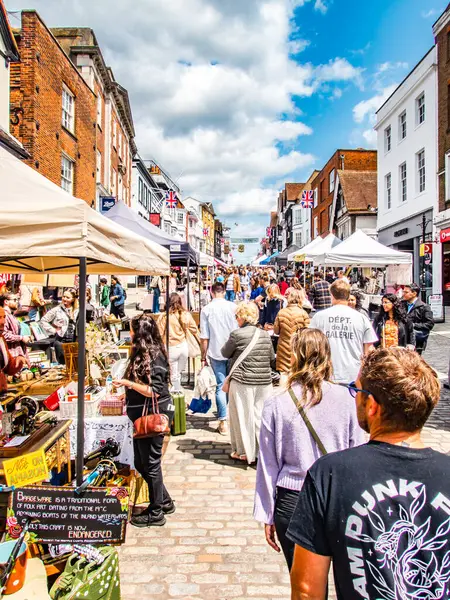 Güneşli bir günde, ana caddedeki açık hava pazarında tezgah ve kalabalıklar var..