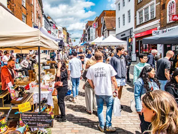Güneşli bir günde, ana caddedeki açık hava pazarında tezgah ve kalabalıklar var..