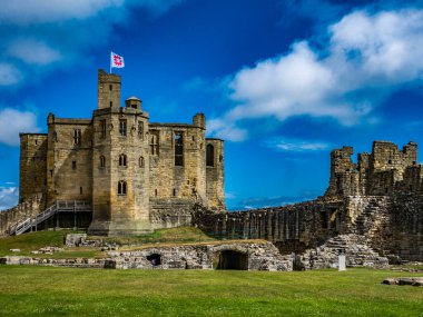 Warkworth Kalesi, Northumberland, İngiltere. Kalan taş duvarlar ve bayrak sende kalsın..