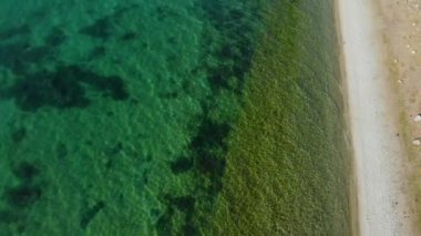 Top view of the shore of a mountain lake with turquoise water. In the clear greenish water you can see the bottom of the lake. Lake Sonkel Kyrgyzstan