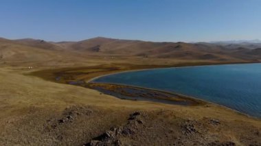 On the shore of a mountain lake in autumn. Traditional place of summer pastures in Kyrgyzstan. On the shore there are yurts in which shepherds live
