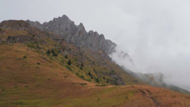 Bulutlar hareket eder ve görkemli uçurumları kapatmaya başlar. Dağlarda yağmurlu bir hava var. Tien Shan dağ sistemi. Kazakistan