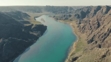 Turistler turkuaz nehri olan muhteşem kanyona bakan bir kayanın üzerinde piknik yapıyorlar. Derin bir kanyondan akan güzel bir turkuaz nehri. Kazakistan. Almaty bölgesi