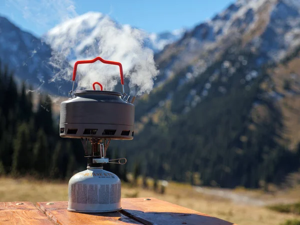 A kettle is boiling on a camp gas burner. Using tourist equipment in the mountains. Preparing a hot drink while hiking