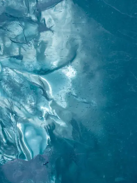 Texture of frozen ice of a mountain lake. The thickness of green-blue ice through which light is visible
