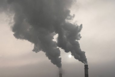 Kalın dumanların çıktığı girişimin bacaları. Gökyüzünün arka planında bir termik santralin bacaları. Karbon yakıtları nedeniyle çevresel sorunlar