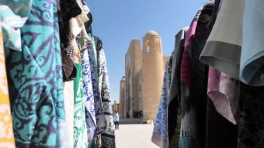Özbekistan 'ın Bukhara kentindeki geleneksel tekstil ve ürünlerle ticaret tezgahları. Ulusal bir şablona sahip kumaş rüzgarda dalgalanıyor