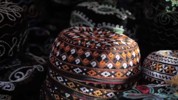 伝統的なウズベキスタンのヘッドドレスの頭蓋骨 刺繍されたオレンジ色のパターンを持つ黒い帽子 中央アジアのお土産 — ストック動画