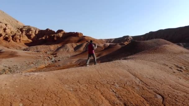 Egy Fickó Kamerával Állványon Végigsétál Egy Dombon Szokatlan Vörös Sziklás — Stock videók
