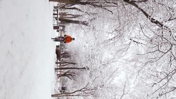 Вертикальні Відеозаписи Хлопця Помаранчевій Куртці Їде Велосипеді Через Зимове Місто — стокове відео