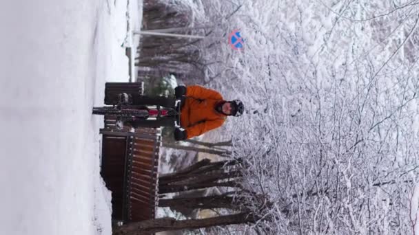 Вертикальні Відеозаписи Хлопця Помаранчевій Куртці Їде Велосипеді Через Зимове Місто — стокове відео