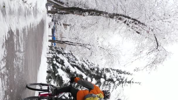 Вертикальна Відеозйомка Велосипедиста Проходить Через Зимове Місто Серед Засніжених Дерев — стокове відео