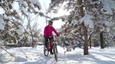 Karlı kışta bisikletli bir kız. Kışın zarafeti. Bisiklet kasklı ve pembe ceketli genç kız açık havada eğleniyor. Yavaş çekim