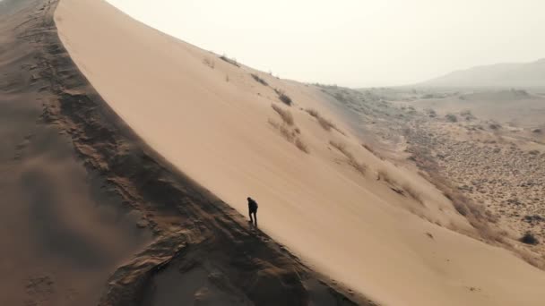 Человек Поднимается Гребню Песчаной Дюны Вершину Жесткая Пустынная Местность Холодный — стоковое видео