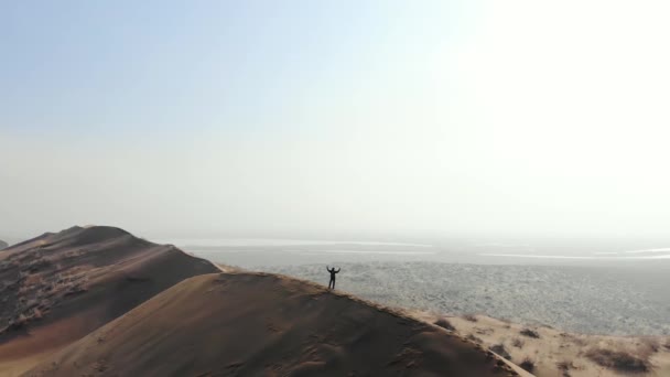 Гребне Огромной Песчаной Дюны Стоит Турист Радуется Достижению Поднимая Руки — стоковое видео