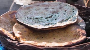 Tandyr fırınında pişirilmiş geleneksel Özbek ekmeği. Sağlıklı otlarla dolu yassı ekmekler. Hasır sepete yeni konmuş sıcak ekmek.