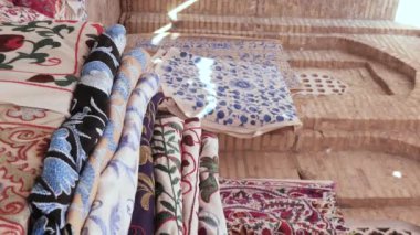 Geleneksel doğu halıları ve el yapımı kumaşların dikey video görüntüleri. Özbekistan 'ın geleneksel zanaatı. Bir zanaatkârın atölyesinde halı satmak. KHIVA, UZBEKİSTAN