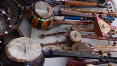 Buhara şehrinin caddesinde müzik aletleri olan bir dükkanın dikey video görüntüleri. Özbekistan. Orta Asya 'da hediyelik eşya ticareti..