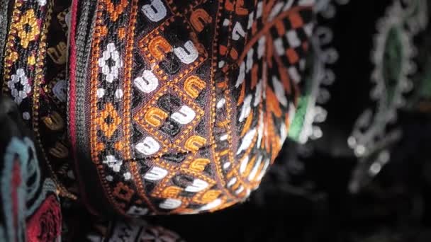 ウズベキスタンの伝統的なヘッドドレスの頭蓋骨の垂直ビデオ映像 刺繍されたオレンジ色のパターンを持つ黒い帽子 中央アジアのお土産 — ストック動画