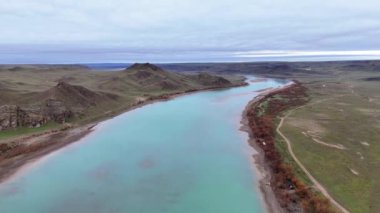 Sabahın erken saatlerinde, baharda nehrin kuş bakışı görüntüsü. Nehir yatağının turkuaz suyu kayalık tepelerin arasında süzülüyor. Ili Nehri, Kazakistan