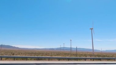 Yol boyunca rüzgar türbinleri yerleştirildi. Arabanın camından rüzgar türbinlerinin görüntüsü. Kazakistan