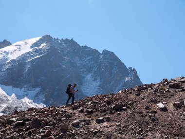 Dağlarda yürüyen sakallı adam. Yazın dağlarda tek başına yürüyüş. Bir adam yüksek dağlardaki kayalık bir tepenin tepesinde yürüyor.