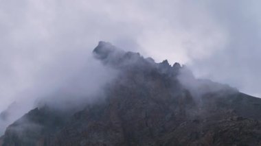 Yazın Talgar Geçidi 'nde sisli bir hava var. Kazakistan 'daki Tien-Shan Dağları. Dağların tepesinde bulutların arasında çıplak kayalar. Bitki örtüsü eksikliği