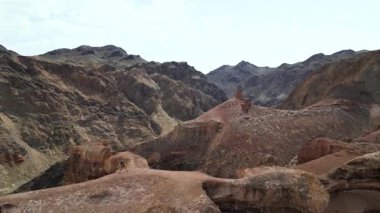 Bir gezgin sıradışı kumtaşı kayalıkları boyunca yürür. Bir turist eşsiz bir dağlık alanda yürüyüş yapıyor. Charyn Kanyonu