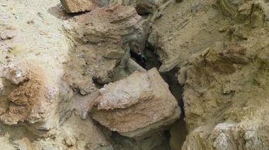 Erkek bir turist, büyük kayalarla dolu kumlu dar bir kanyondan geçiyor. Yalnız bir turist, yaban ve çorak bir alanda, yürüyüş direkleri ve hafif bir sırt çantasıyla.