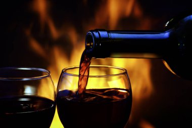 Şöminenin yanındaki iki bardağa kırmızı şarap dök.