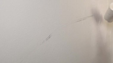 Duvarı boyayan tekerlekli bir erkek el.