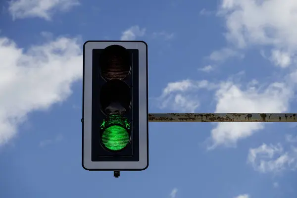 closeup of traffic light with green light on, blue sky