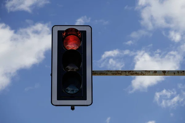 closeup of traffic light with red light on, blue sky